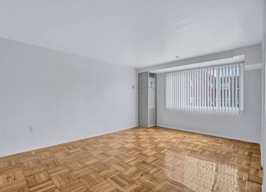 A room with a wooden floor and a door leading to another room.