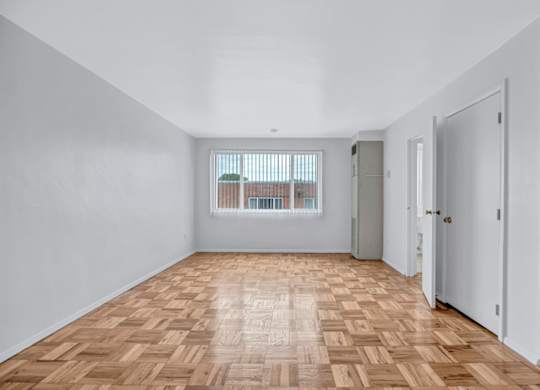A room with wooden flooring and white walls.