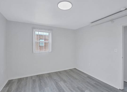 A room with a window and a wooden floor.