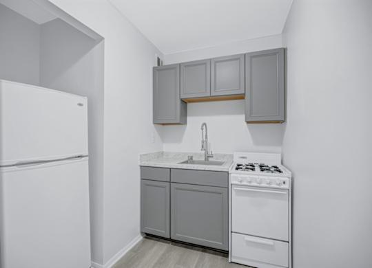 A small kitchen with white appliances and grey cabinets.