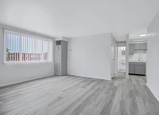 A spacious room with a wooden floor and white walls.