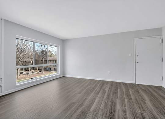 A room with a large window and a wooden floor.