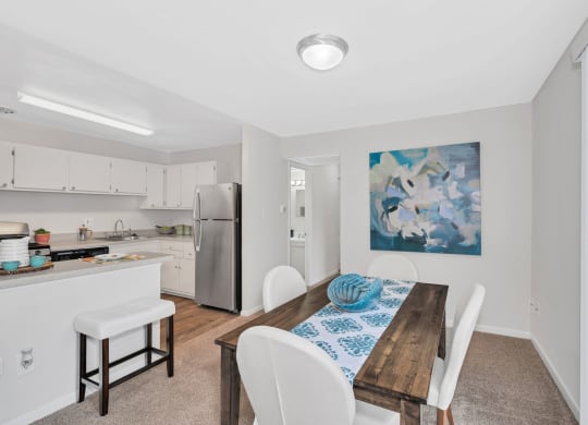 a dining room with a table and chairs and a kitchen in the background