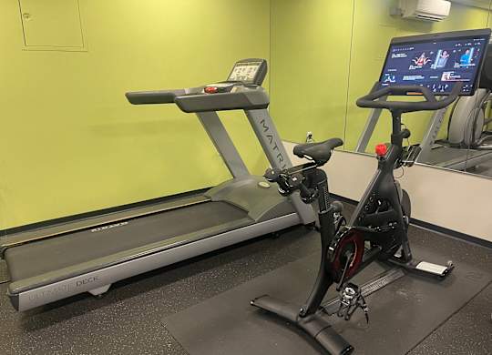 A treadmill and a stationary bike are in a gym.