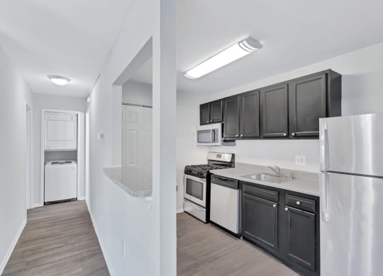a kitchen with black cabinets and white appliances and a refrigerator
