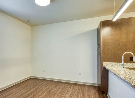 an empty living room with a kitchen and a large window