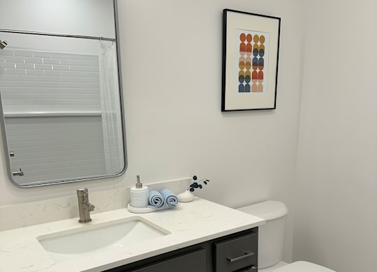 A bathroom with a toilet, sink, and a mirror.