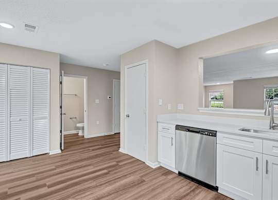 A kitchen with white cabinets and a wooden floor.