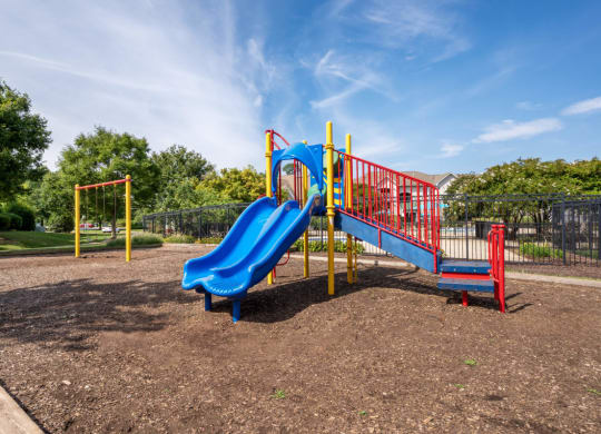 a playground with a blue slide and a red swing set