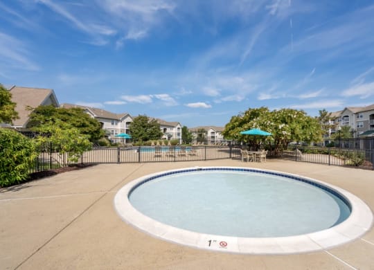 an oval swimming pool with a fence and apartments in the background
