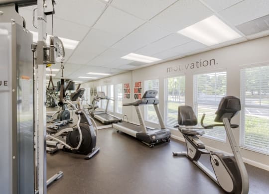 a gym with cardio equipment and windows in a building