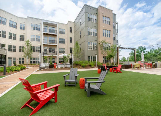 a courtyard with red chairs and lawn chairs in front of an apartment building