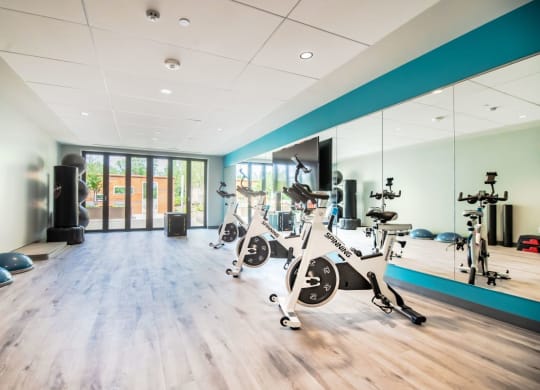 a gym with exercise bikes and weights on a wooden floor