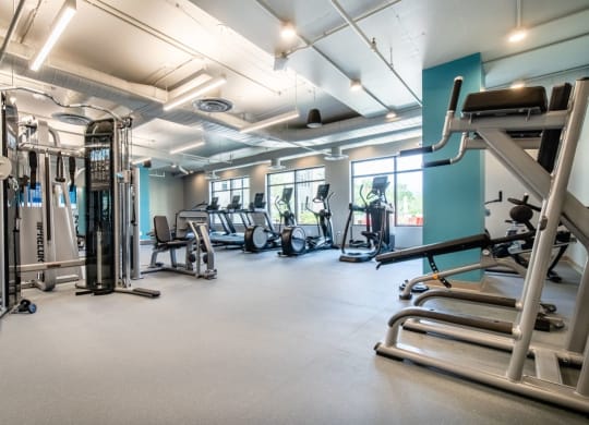 a gym with cardio equipment and weights on the floor