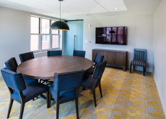 a conference room with a round table and chairs and a television