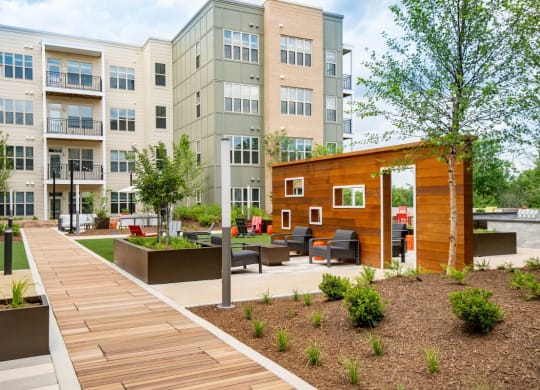 a courtyard with a wooden walkway and benches in front of an apartment building