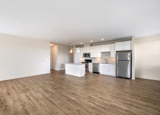 an empty living room and kitchen with a wood floor