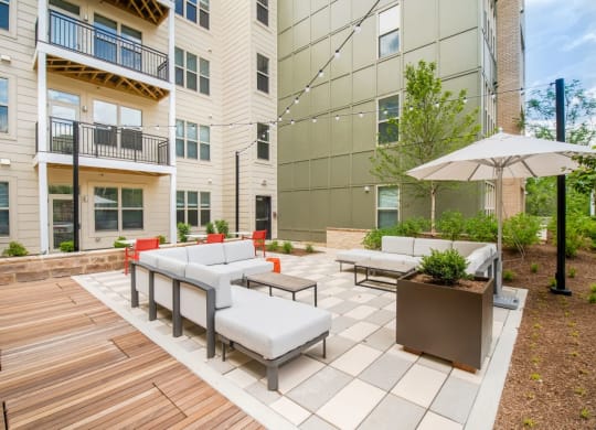 an outdoor patio with couches and chairs and an umbrella