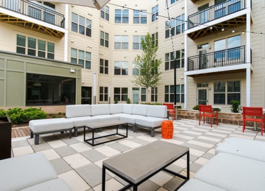 an outdoor patio with couches and tables in front of an apartment building