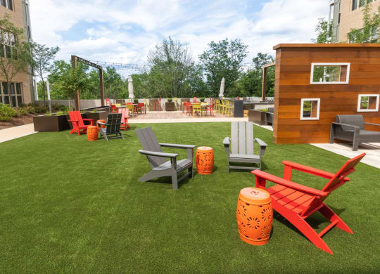 a lounge area with chairs and a fire pit on a lawn