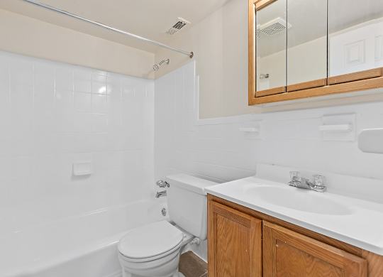 A white bathroom with a toilet, sink, and mirror.