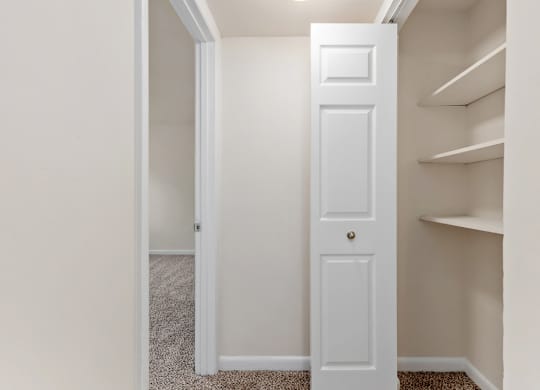 A white door is in a hallway with a carpeted floor.
