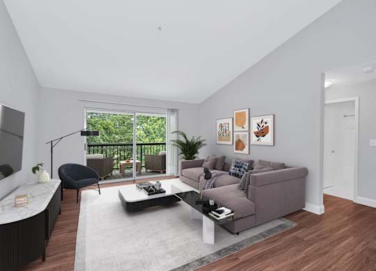 A furnished luxury apartment living room with balcony showing wooded view.