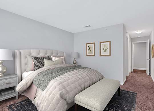 A spacious apartment bedroom with large bed and bench at the foot and hallway to closet and bathroom.
