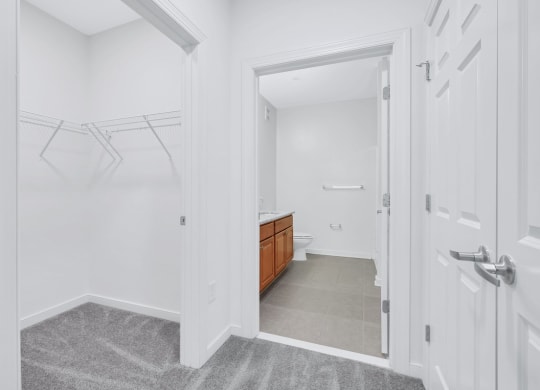 a white bathroom with a walk in closet and a toilet