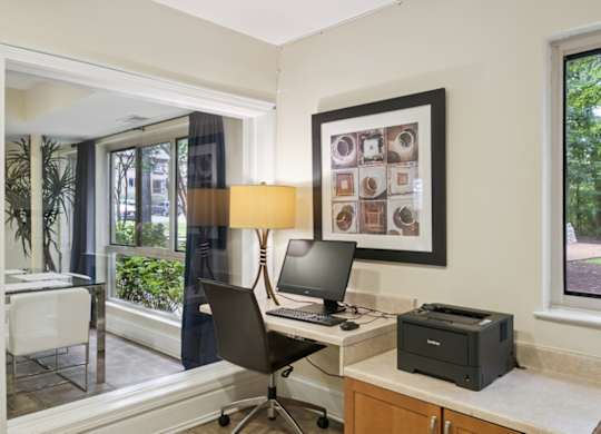 A room with a desk, chair, and a window with a view of trees.