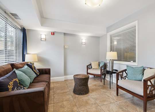 A living room with a brown couch, two chairs, and a table with lamps.