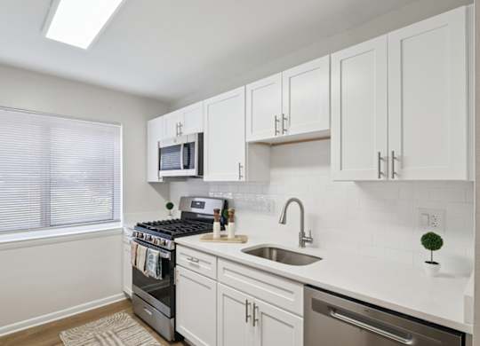 A kitchen with white cabinets and a stove top oven.