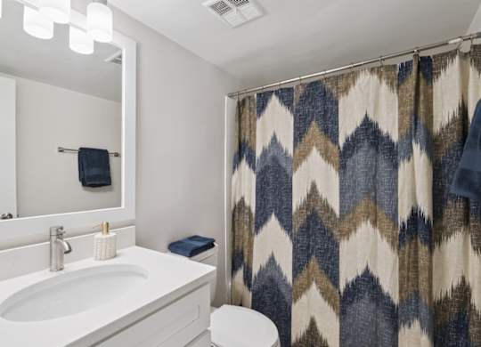 A bathroom with a white sink and a shower curtain with a chevron pattern.