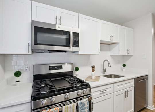 A modern kitchen with white cabinets and a stainless steel stove.