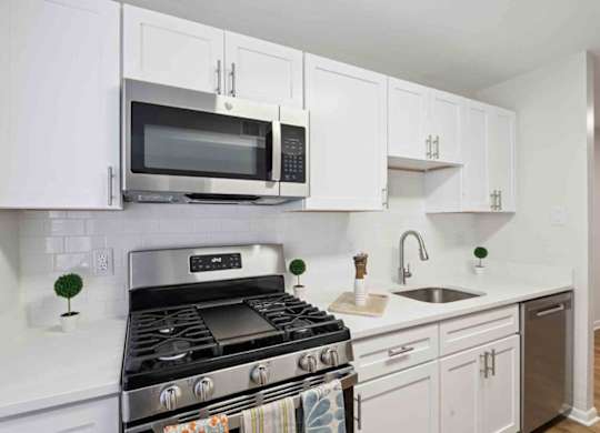 A modern kitchen with white cabinets and a stainless steel stove.