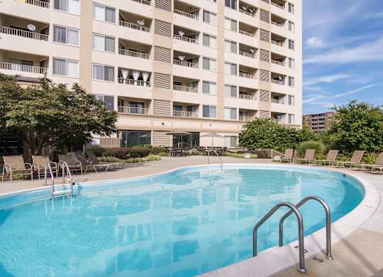 A large swimming pool in front of a multi-story apartment building.