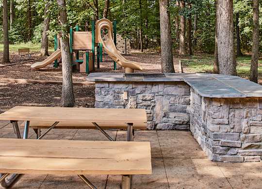 A playground with a slide, picnic table, and a stone wall.
