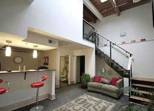a room with a staircase and a living room with red chairs