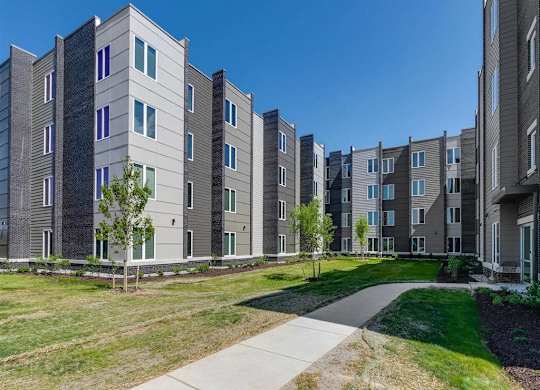 an exterior view of an apartment building with grass and trees