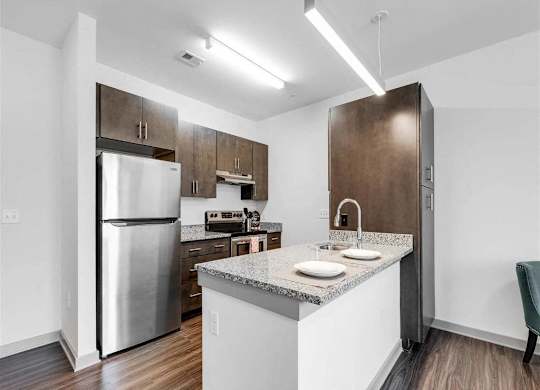 A kitchen with a refrigerator, sink, and cabinets.