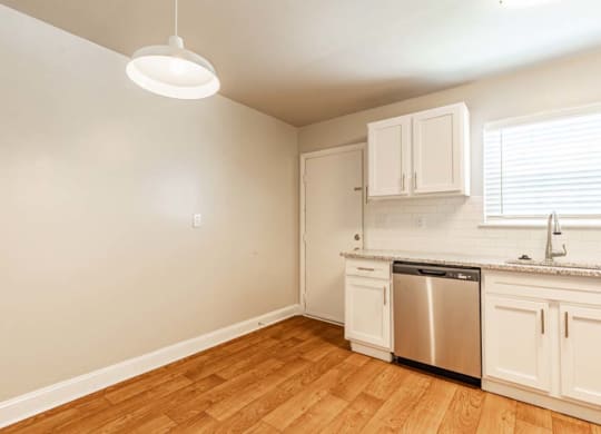 an empty kitchen with white cabinets and a sink and a dishwasher