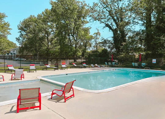 a swimming pool with red chairs around it