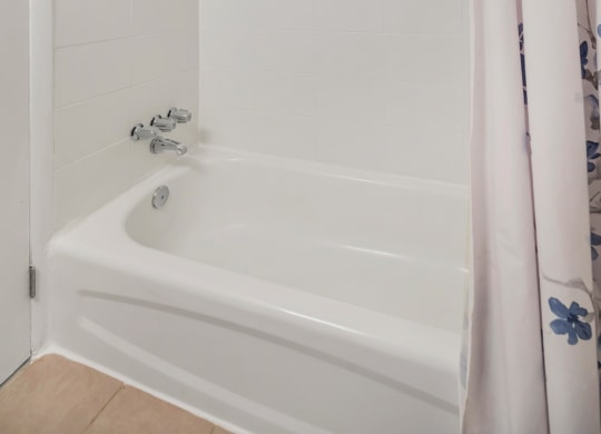 a white tub sitting next to a white shower curtain