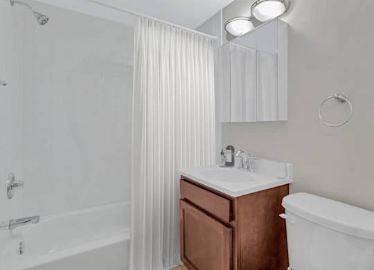 A white bathroom with a brown vanity and a white toilet.