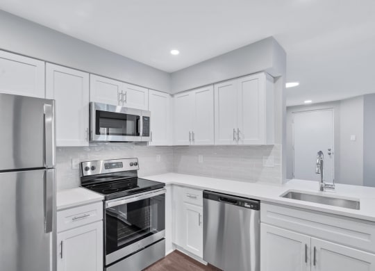 Immaculate kitchen featuring sleek stainless steel appliances and pristine white cabinets.