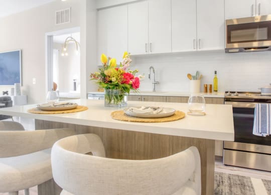 a kitchen with white cabinets and a white island with a vase of flowers on it