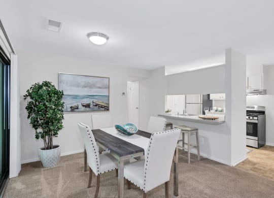 a dining area with a table and chairs and a kitchen in the background