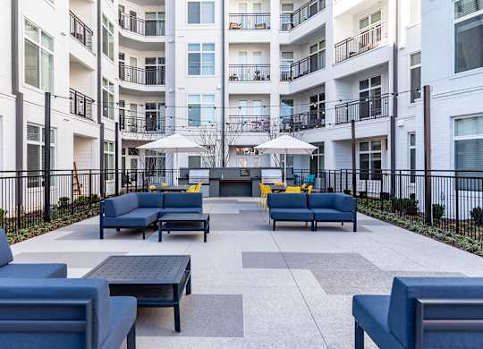 a large patio with furniture and umbrellas in front of an apartment building