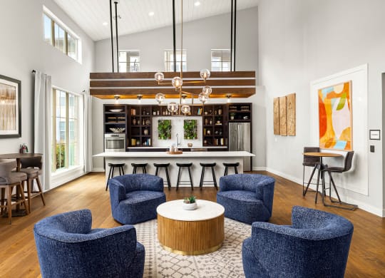 a living room with blue chairs and a kitchen with a bar