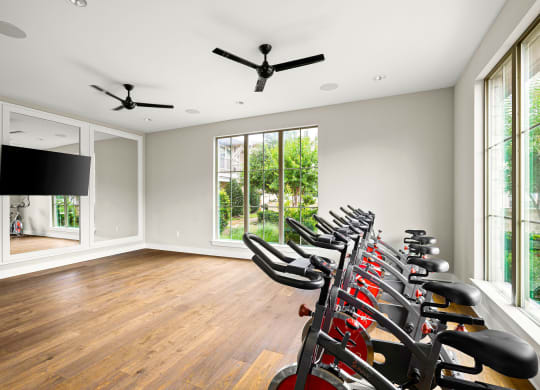 the home gym has a wall of windows and a row of exercise bikes